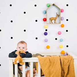 Chambre de bébé décorée avec des autocollants muraux en formes de ronds de couleur noir.